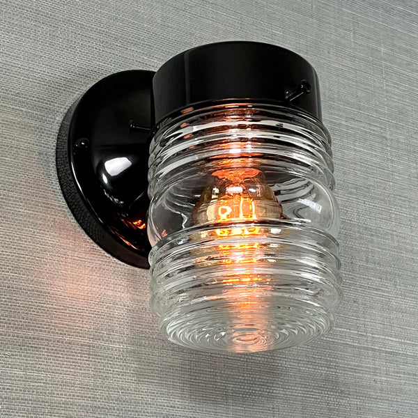 Post-War Era Porch Sconce. Vintage Jelly Jar Glass Shade. The Post-War porch sconce features a vintage jelly jar-style glass shade with an iconic fresnel rounded bottom lens. The black sconce is new and U.L. Listed. The fixture has been cleaned and detailed. Available at www.vintporium.com