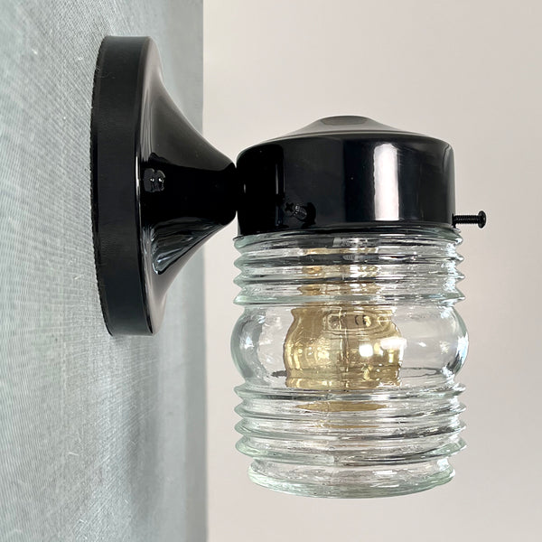 Post-War Era Porch Sconce. Vintage Jelly Jar Glass Shade. The Post-War porch sconce features a vintage jelly jar-style glass shade with an iconic fresnel rounded bottom lens. The black sconce is new and U.L. Listed. The fixture has been cleaned and detailed. Available at www.vintporium.com