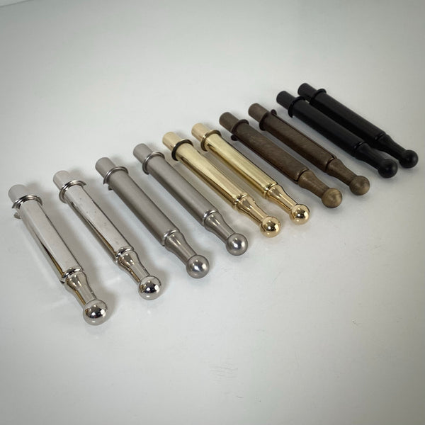 Collection of window sash spring bolts arranged in a row showing various metallic finishes on a light background.