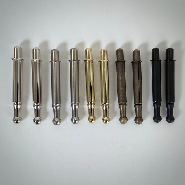 Top-down comparison view of window sash spring bolt hardware pairs in polished nickel, brushed nickel, polished brass, antique brass, and oil rubbed bronze finishes