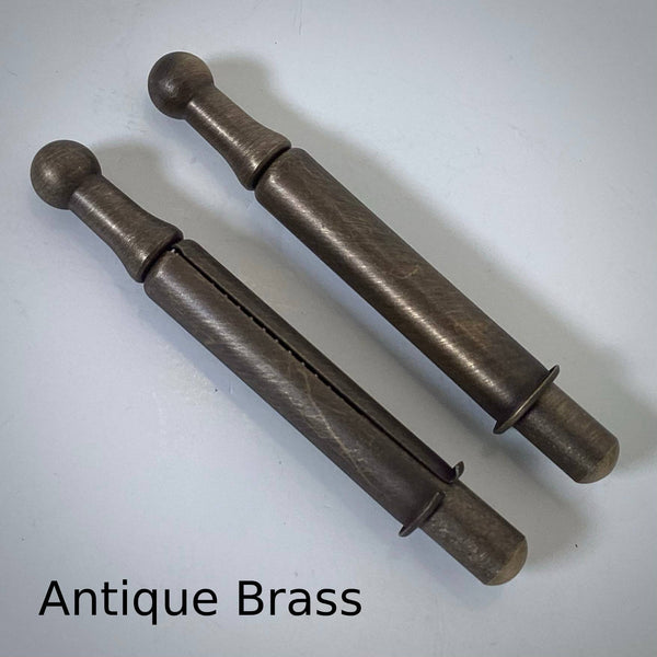 Pair of antique brass window sash spring bolts displaying dark aged metal patina and ball pull knobs.