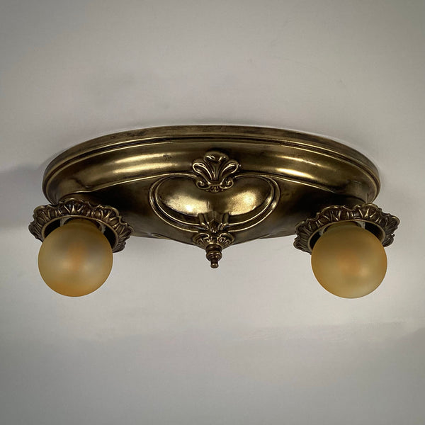 French Provincial style antique brass double light flush mount ceiling fixture turned off.