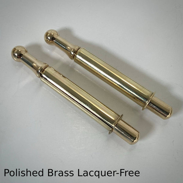 Pair of lacquer-free polished brass window sash spring bolts with a shiny gold reflective finish.