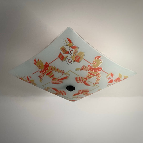 Unlit glass shade shown from a diamond angle detailing colorful ABC blocks and clown artwork.