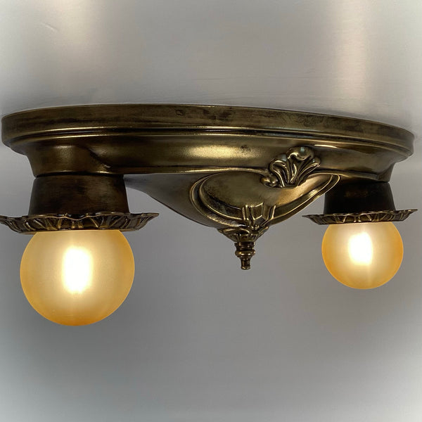 Side profile view of a two-light antique brass flush mount ceiling fixture illuminated.