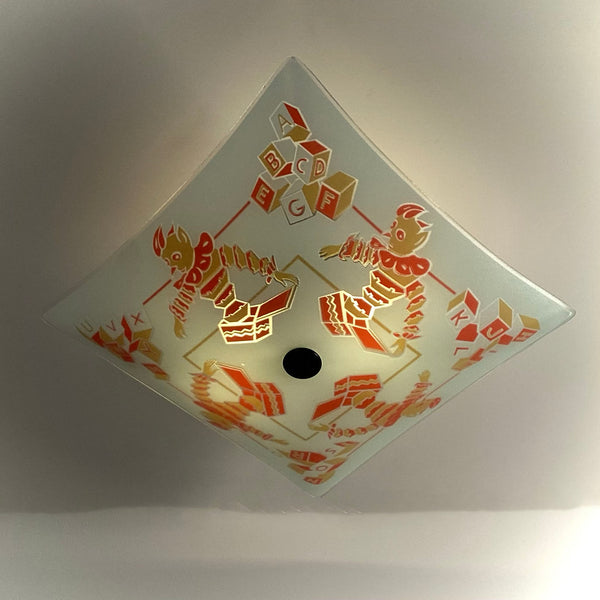 Overhead diamond-oriented shot of a illuminated vintage children's room glass light fixture with center finial.