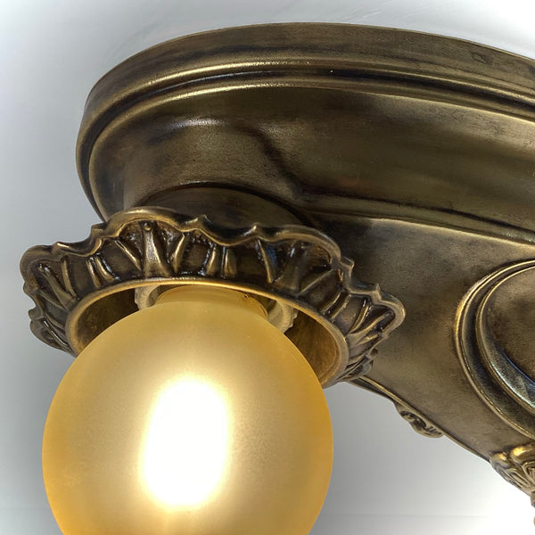 Close-up of a decorative scalloped socket cup on an antique brass flush mount light fixture.