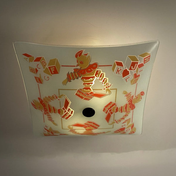 Direct bottom-up view of lit nursery glass light shade highlighting warm light glow through frosted glass.