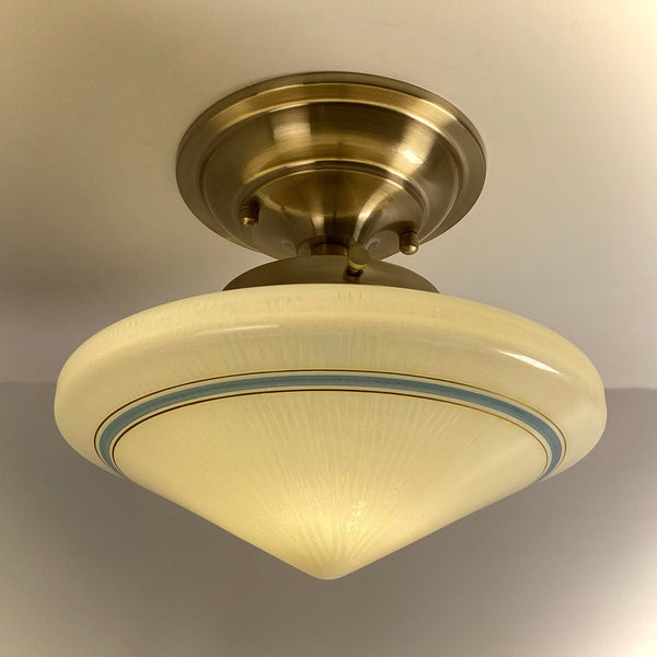 Antique Art Deco schoolhouse ceiling light with a cream opal glass shade and a blue band, mounted on a brand new satin brass semi-flush fixture.