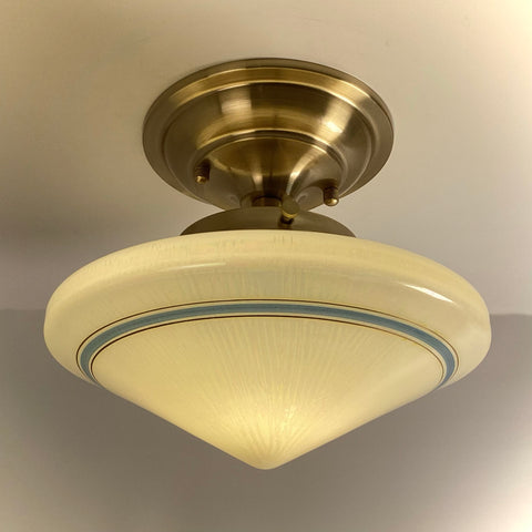 Antique Art Deco schoolhouse ceiling light with a cream opal glass shade and a blue band, mounted on a brand new satin brass semi-flush fixture.