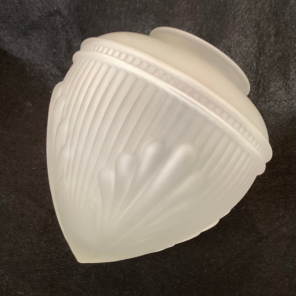 Angled side view of a frosted white art deco glass lamp shade featuring ribbed details and raised embossed fan patterns against a dark background.