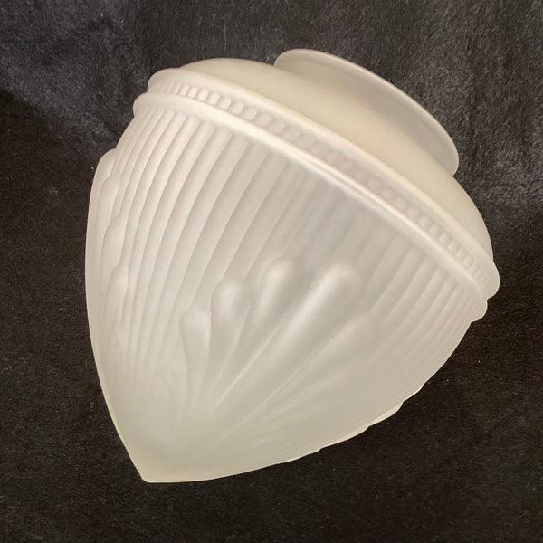 Angled side view of a frosted white art deco glass lamp shade featuring ribbed details and raised embossed fan patterns against a dark background.