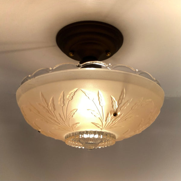 Illuminated vintage Art Deco semi-flush mount ceiling light with a frosted glass shade and embossed wheat leaf motif.
