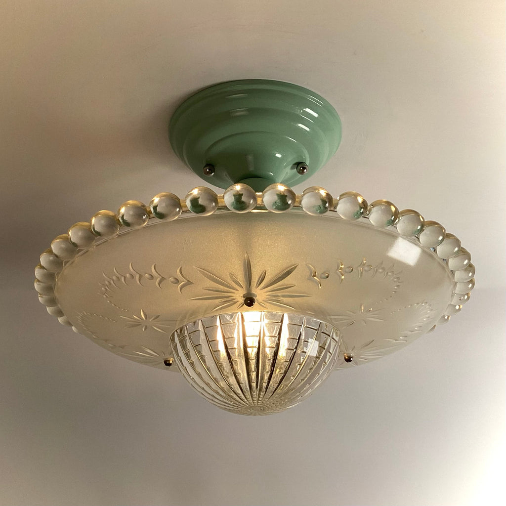 Antique semi-flush mount ceiling light with a mint green base and an illuminated frosted starburst glass shade.