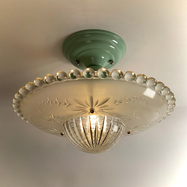 Antique semi-flush mount ceiling light with a mint green base and an illuminated frosted starburst glass shade.