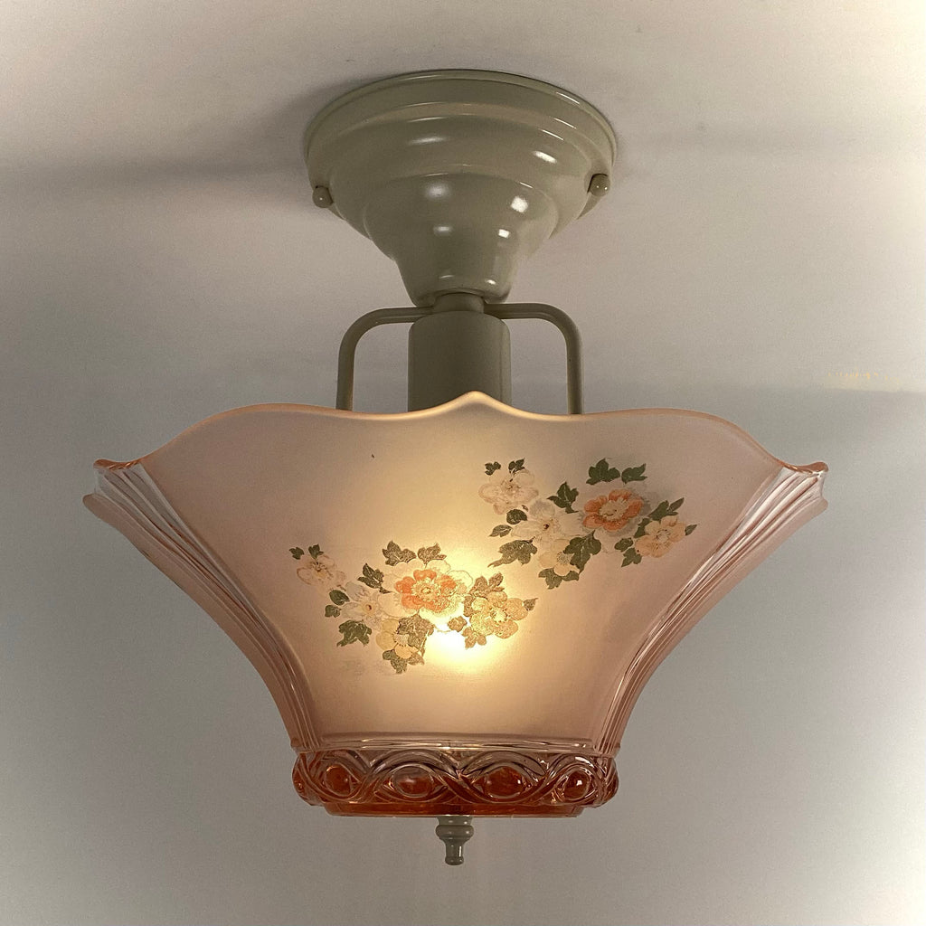 Vintage pink frosted depression glass flush mount ceiling light fixture illuminated with floral pattern.