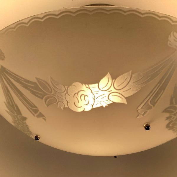 Detail of illuminated floral motif on vintage 1950s frosted glass bowl semi flush ceiling light fixture