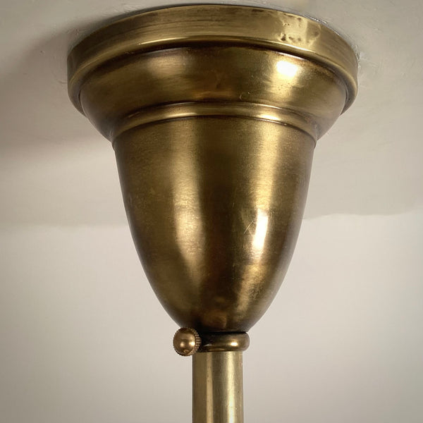 Close-up detail of antique brass ceiling rose canopy mount and set screw.