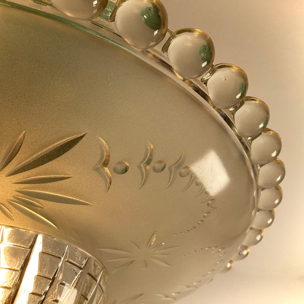 Detailed close-up shot of the clear beaded edge and etched glass pattern on an antique ceiling light shade.