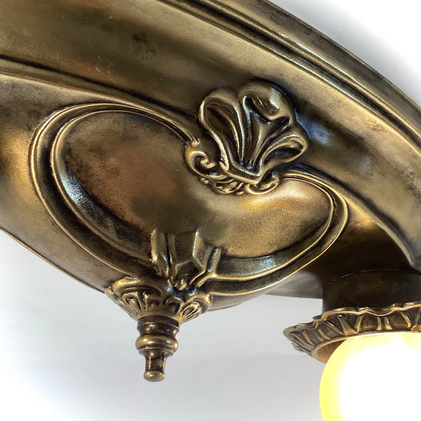 Close-up detail of the carved center finial and scrollwork on a vintage brass ceiling plate.