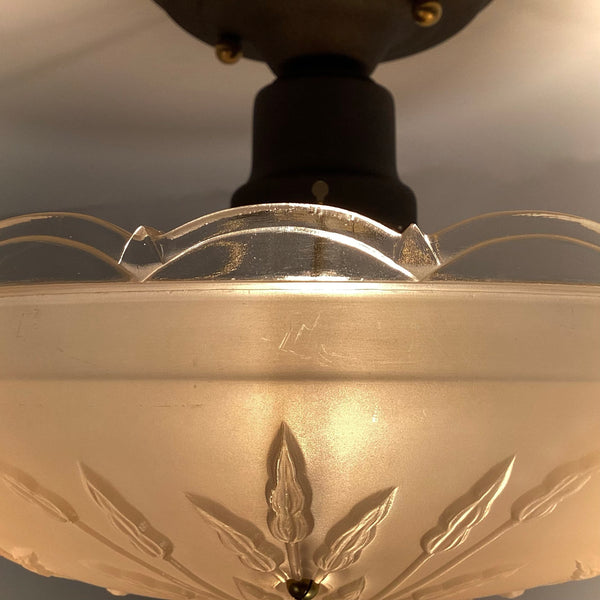 Close-up detail of the clear scalloped rim and embossed floral design on a vintage frosted glass ceiling light bowl.