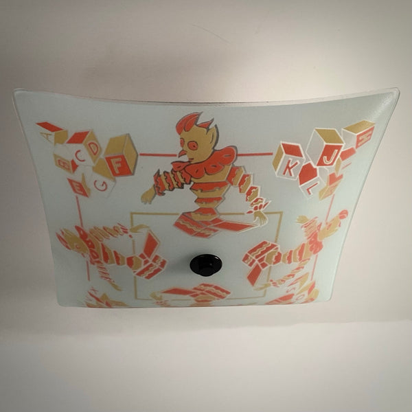 Direct bottom-up view of unlit vintage glass ceiling shade showing detailed clown and alphabet block patterns.