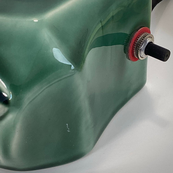 Detailed shot of the black toggle power switch and red washer on the side of a vintage ceramic lamp.