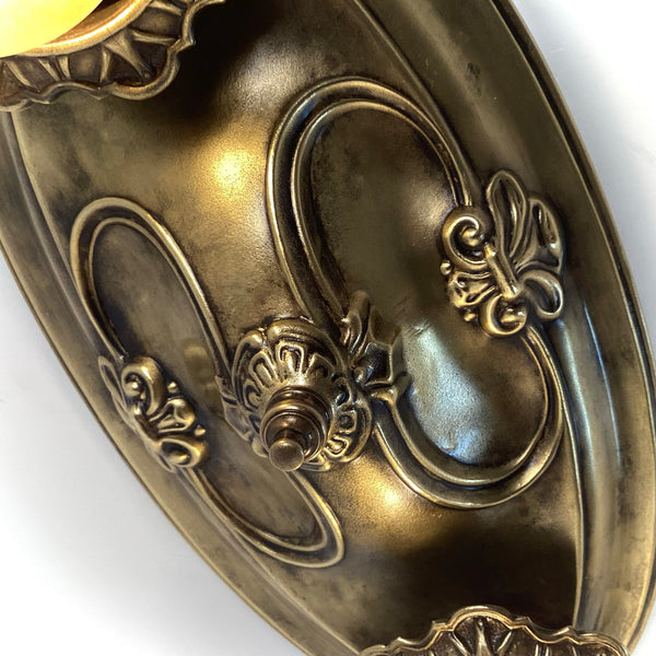 Macro shot highlighting the intricate scrollwork and aged brass patina on the ceiling canopy.