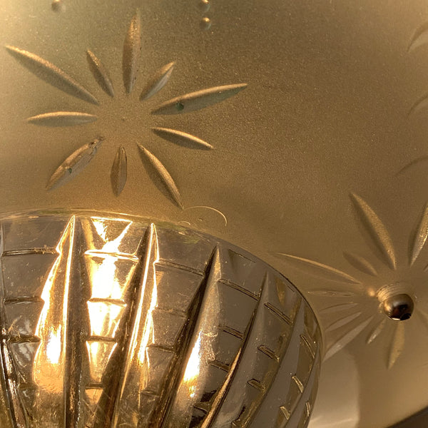 Macro close-up of a vintage ceiling light shade showing the deeply cut starburst patterns and a textured, ribbed clear glass diffuser.