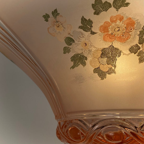 Macro view of the hand-painted style floral decal on pink frosted glass above an embossed rim base.