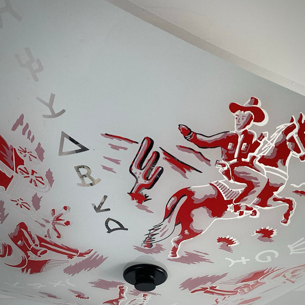 Up-close view of a red cowboy riding a horse printed on a vintage frosted square glass light shade.