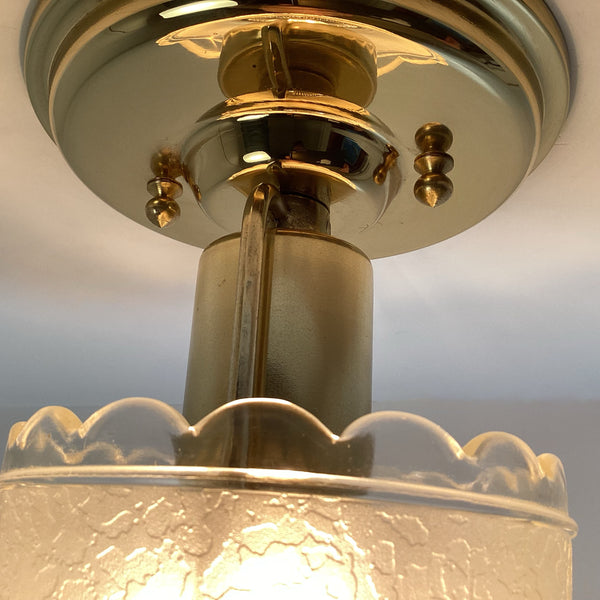 Angled macro shot showing the brass ceiling canopy with decorative knurled screws and inner brass neck.