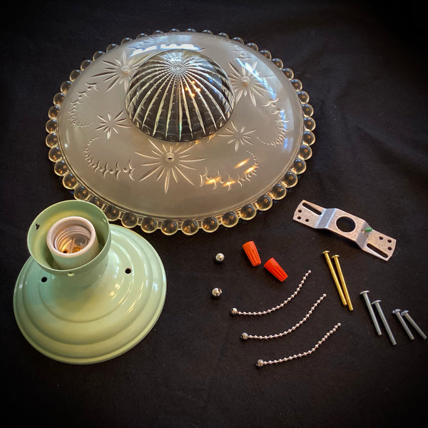 Flat lay view of the unassembled vintage ceiling light parts, including the green canopy base, etched glass shade, mounting bracket, screws, wire nuts, and ball chains.