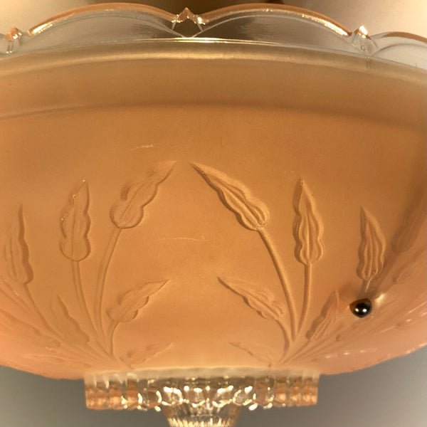 Close profile view of the pink frosted glass shade highlighting the scalloped upper edge, mounting screw hole, and clear glass bottom rim.