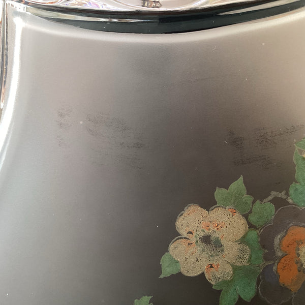 Close-up of faint surface wear marks and floral print on the frosted pink glass body.
