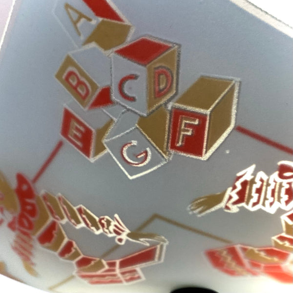 Detailed shot of painted toy blocks showing letters A through G on a frosted glass ceiling light fixture.
