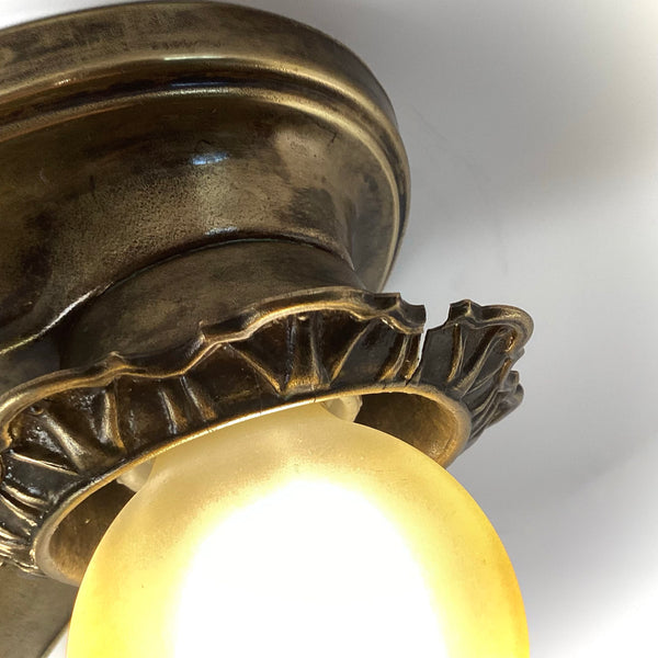 Close-up detail of the fluted socket rim and lit amber glass globe bulb.