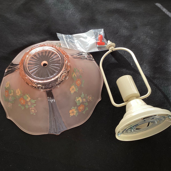 Unassembled vintage pink glass floral lamp shade laid flat next to its white metal ceiling canopy socket base and wiring hardware.