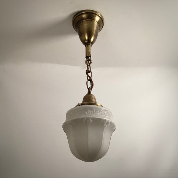 Antique brass hanging pendant lamp with textured frosted glass shade turned off.