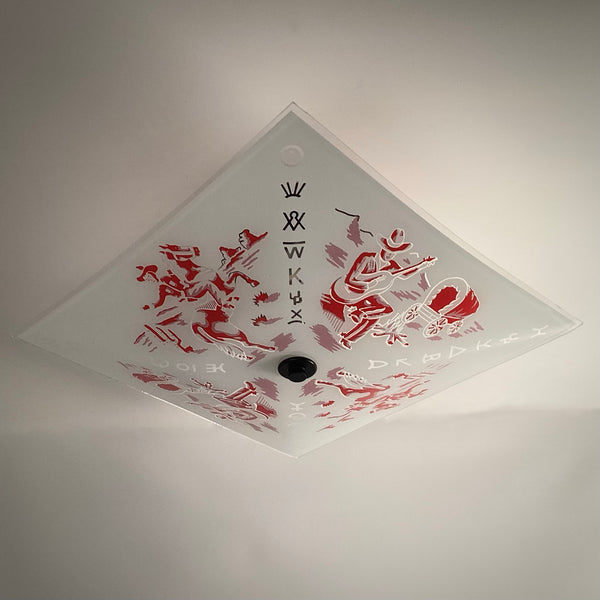 Angled low-angle view of a vintage frosted glass ceiling light shade decorated with red Western cowboy graphics and brand symbols.