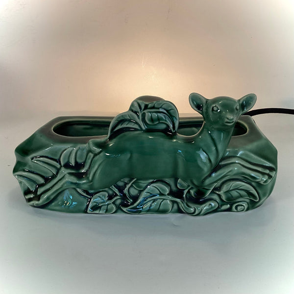 Direct front view of a retro 1950s green glazed ceramic deer lamp used for ambient television lighting.