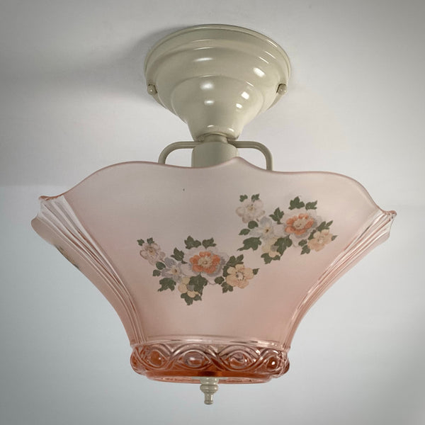 Pink frosted glass ceiling light fixture with painted floral design and white flush mount canopy, turned off.