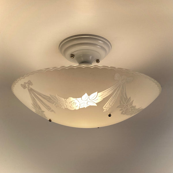 Vintage 1950s semi flush mount ceiling light lit showing enameled floral garland pattern on frosted glass bowl shade