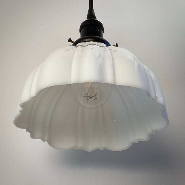 Underside view of a white glass scalloped pendant light shade showing the socket.