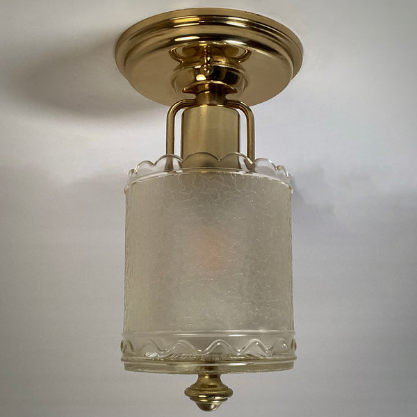 Front view of an unlit vintage flush mount ceiling light with polished brass canopy and scalloped textured glass shade.