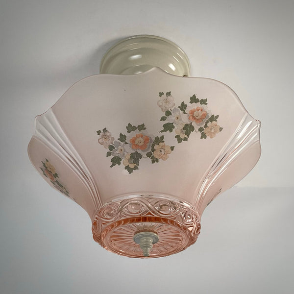 Underside view looking up at a flared pink glass lamp shade showing ribbed sides and floral decals.