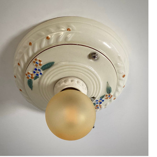 A profile shot of an antique porcelain ceiling light fixture with embossed detailing.