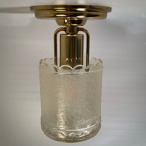 Straight-on side view of an unlit brass semi-flush light fixture featuring an open scalloped textured glass shade.
