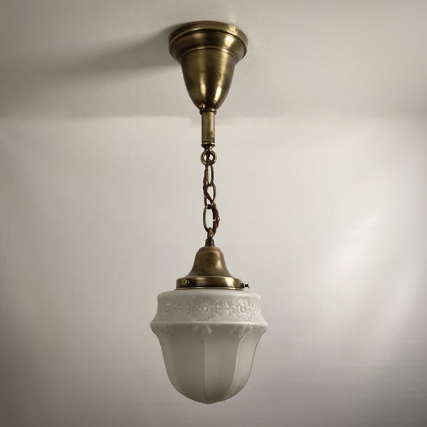 Full shot of brass pendant hanging light fixture with frosted floral pattern glass shade unlit.