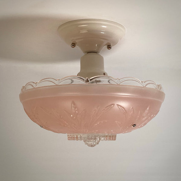 Profile view of a vintage pink frosted glass light fixture with clear rim detail mounted on a white ceiling base.